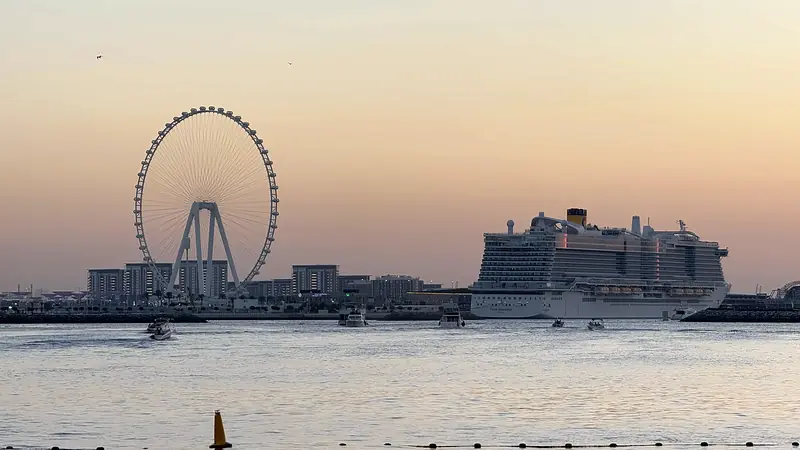 The Ain Dubai observation wheel and a cruise ship on the water at sunset