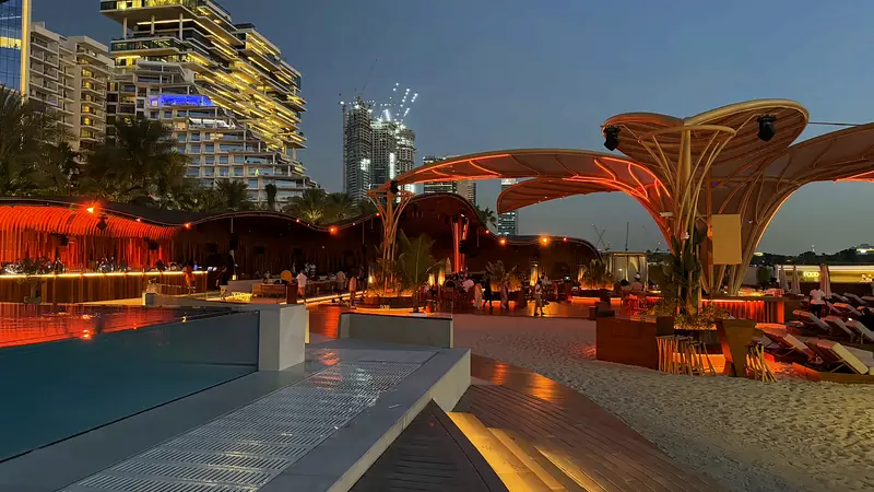 A beachfront pool and lounge area in Dubai lit up at dusk